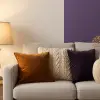 Cozy living room décor with sofa, lamp, and decorative cushions in warm and purple tones.